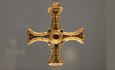 A gold cross pendant with arms inlaid with precious stones.