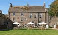 View of the Lord Crewe Arms on a bright sunny day with people sat in the garden under white umbrellas.