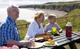 Family having picnic at table on grassland at Nose's Point