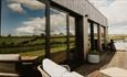 View of outdoor seating area and hot tub at Sandpiper lodge. With countryside view reflected in window.