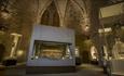 An octagonal medieval room with an arched ceiling, containing cases for museum exhibits.