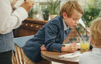 Child in suit drinking through a straw