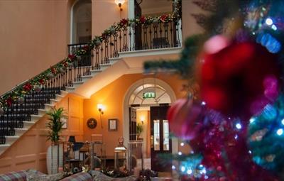 Seaham Hall staircase decorated with a Christmas Garland and Christmas Tree in foyer