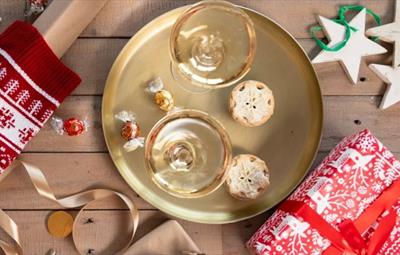 A tray with glasses of wine, mince pies and chocolates