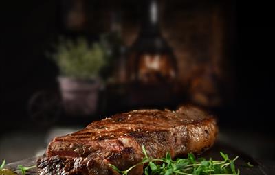 Steak with green garnish on the side. Fireplace in background.