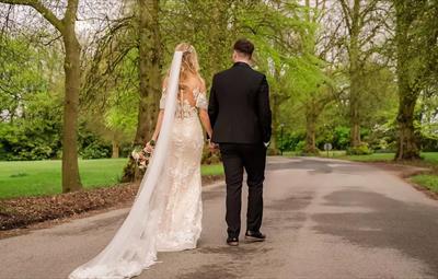 Bride and Groom walking hand in hand through the trees at Redworth Hall Hotel