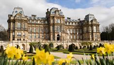 The exterior of The Bowes Museum and its grounds on a sunny day.
