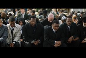 a crowd of people with their heads bowed, praying