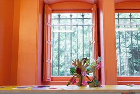 Flowers in front of a window that leads to a view of trees.