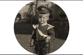 Black and white photo of a child in military clothing.