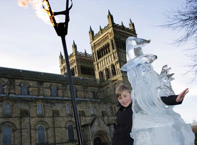 child poses with ice culture and flame lit torch outside Durham Cathedral.