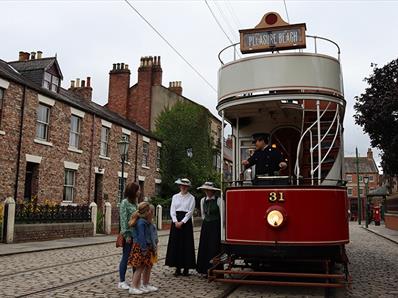 Image of the 1900s Town Street at Beamish Museum, people waiting to board the tram.