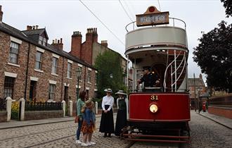 Image of the 1900s Town Street at Beamish Museum, people waiting to board the tram.