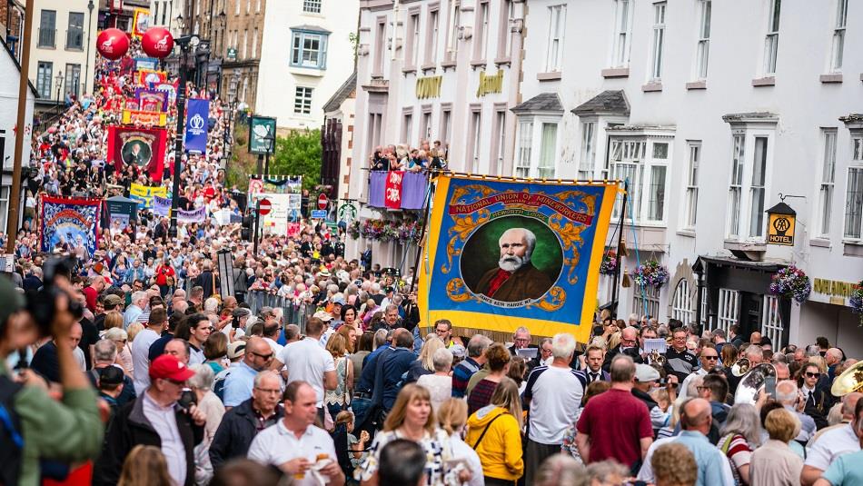 Durham Miners' Gala. Crowds enjoying the Gala outside of the County Hotel. Colliery Banners can be seen as the Bands march through the streets.