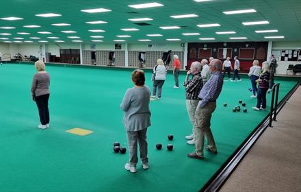 Image of Durham Indoor Bowling Club interior. Several people are enjoying a game.