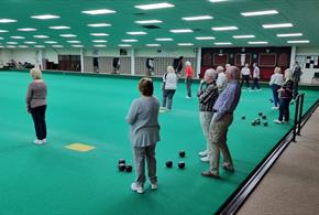 Image of Durham Indoor Bowling Club interior. Several people are enjoying a game.