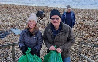 Three people participating in a beach clean at Seaham, carrying bags of rubbish. 
