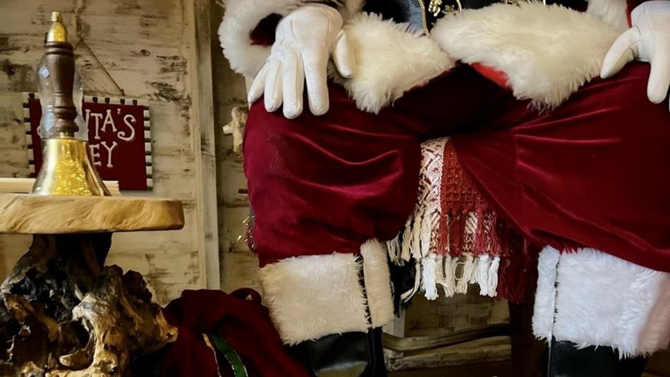 Close up of Santa's legs sitting in a chair beside a table with a gold bell Close up of Santa's legs sitting in a chair beside a table with a gold bell