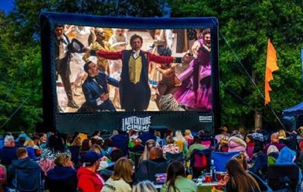 A crowd enjoying a Sing-A-Long outdoor cinema experience in the stunning grounds of Raby Castle.