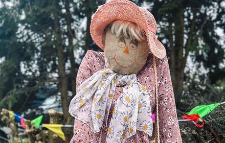 Scarecrow dressed in a floral scarf and pink hat at South Causey Inn.