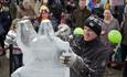 man craves an ice sculpture with crowd watching from behind at the popular Fire and Ice Festival in Durham