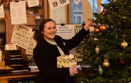 Image of a staff member decorating a Christmas Tree at Beamish.