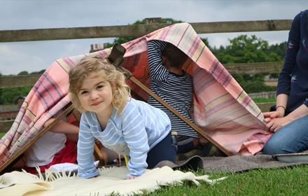 Children making a den with blankets and a wooden clothes horse