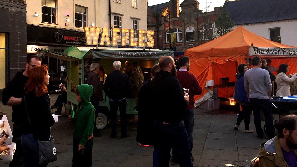 People enjoying waffles and a variety of stalls at Bishop Auckland Full Moon Market.