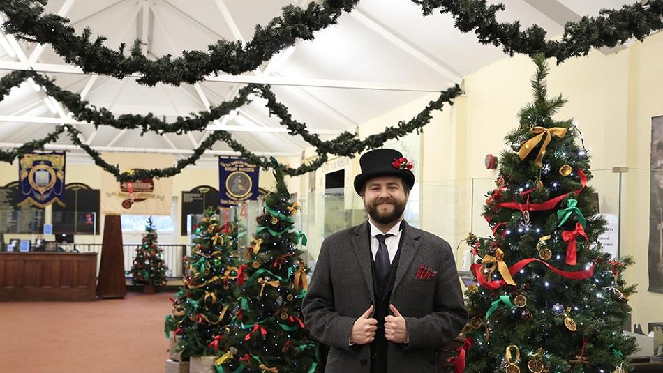 A costumed member of staff in front of Christmas Trees at Beamish Museum's entrance building.
