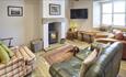 Cosy living are in cottage with real log burner, stone tiled floor and green leather sofa. Wooden beams on the ceiling.