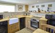 Wooden kitchen unit with butchers sink. Fitted appliances and spotlights in the ceiling.