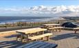 Outdoor seating area wooden picnic benches sea and beach in background