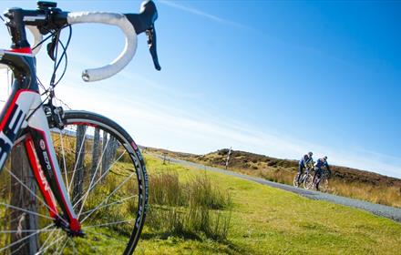 Two people cycling in the Durham Dales with close up view of a bicycle in fore ground.