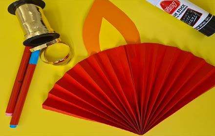 Image of craft materials: glue, ribbon, coloured pens and a paper made into fan.