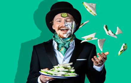 Photo of man in top hat and tails throwing a cucumber sandwiches.