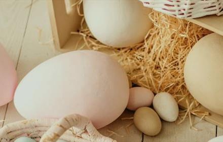 Large and small eggs, two large eggs in box of straw. Part of basket with egg