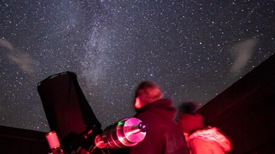 Image of an astronomer under a starry sky.