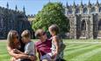 Image of a family sitting on the lawn in front of Auckland Castle on a sunny day.