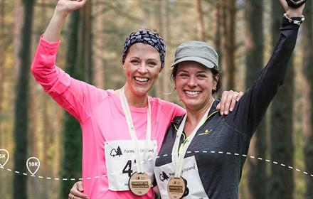 Two women taking part in a run in forest.