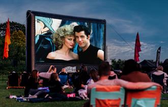 Grease Lightning outdoor cinema at Raby Castle. Crowds enjoying the film outdoors.