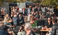 Image of crowds sitting around tables, enjoying their food, and people visiting stalls at the Chester-le-EATS event.