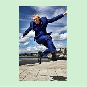 Jeremy Vine jumping in the air, wearing a blue suit.