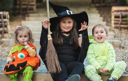 Image of three children dressed in Halloween costumes at Raby: a pumpkin, a witch and a goblin.