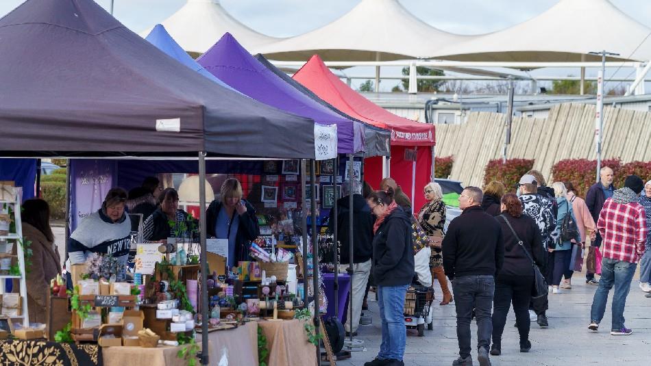 outdoor market at Dalton Park, different coloured stalls. People walking past and looking at stalls.