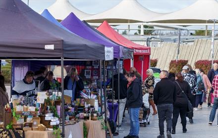 outdoor market at Dalton Park, different coloured stalls. People walking past and looking at stalls.