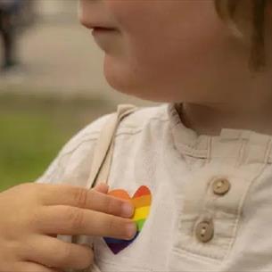 Small child with a rainbow heart shaped sticker on top.