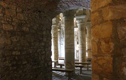 Photograph looking in to the Norman Chapel and Durham Castle, showing several illuminated stone columns beside thick stone walls