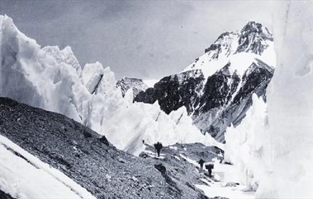 Black and White photograph of Everest with walkers.  'Passing through the "Trough" enroute to camp 3' from the Bentley Beetham Collection