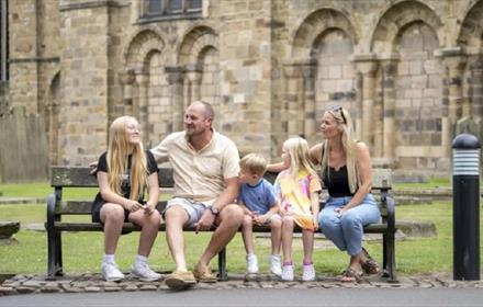 Family sitting on bench in front of Durham Cathedral