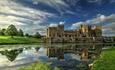 Raby castle with lake in foreground, the castle is reflected in the lake.  Blue skies, countryside.  Image credit David Grey